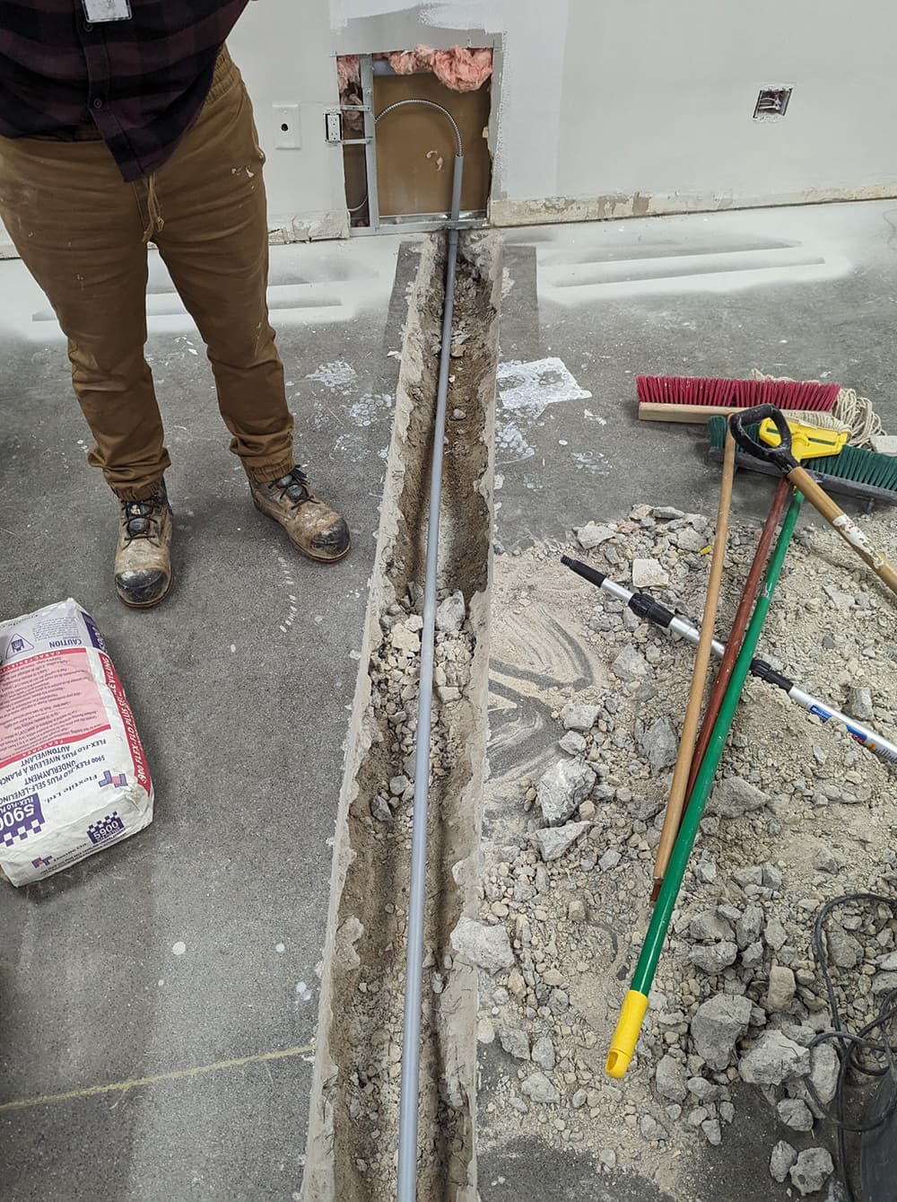 Concrete floor trench with new conduit during a renovation