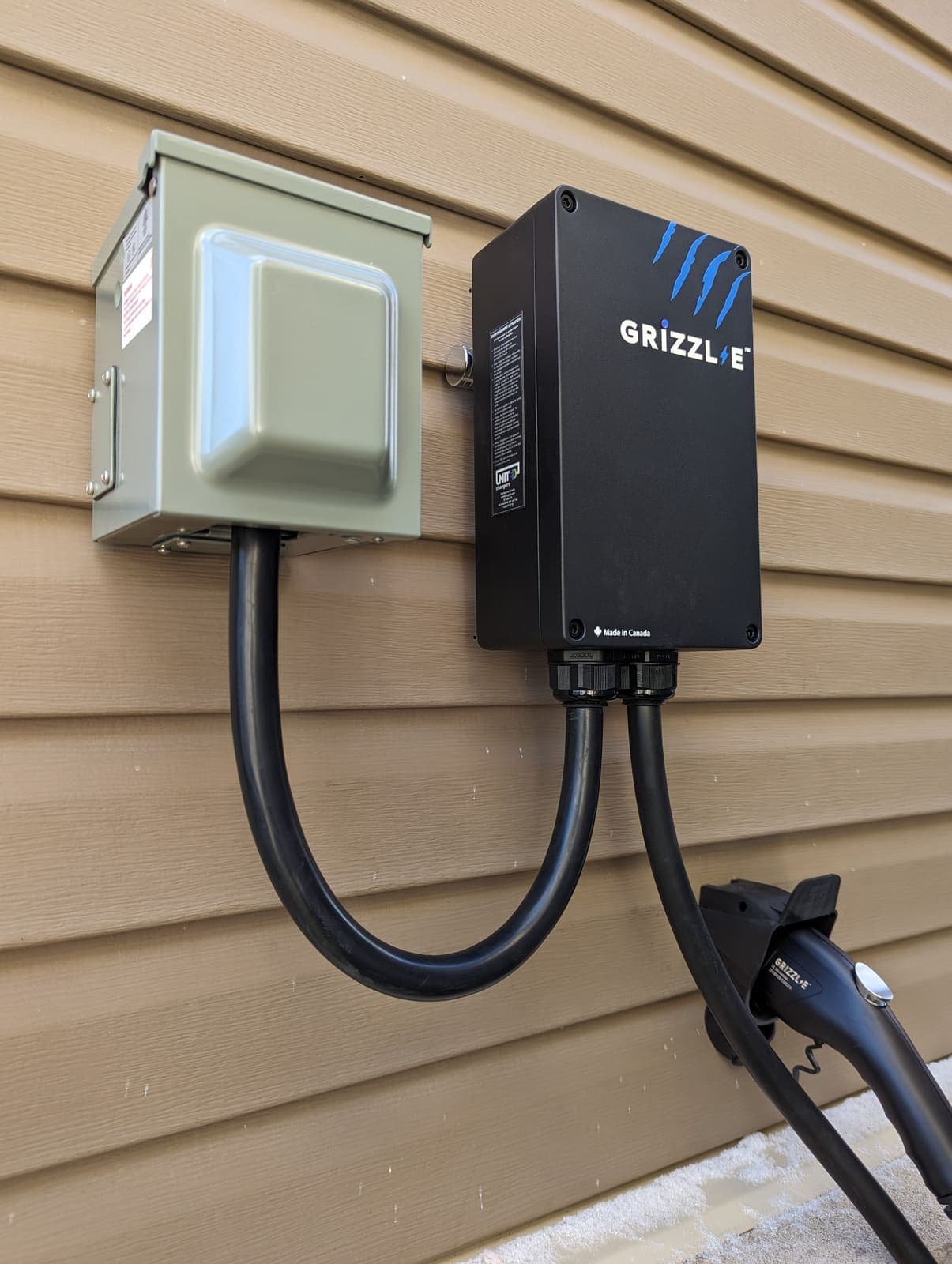 Grizzl-E EV charger installed on exterior siding with a weatherproof disconnect