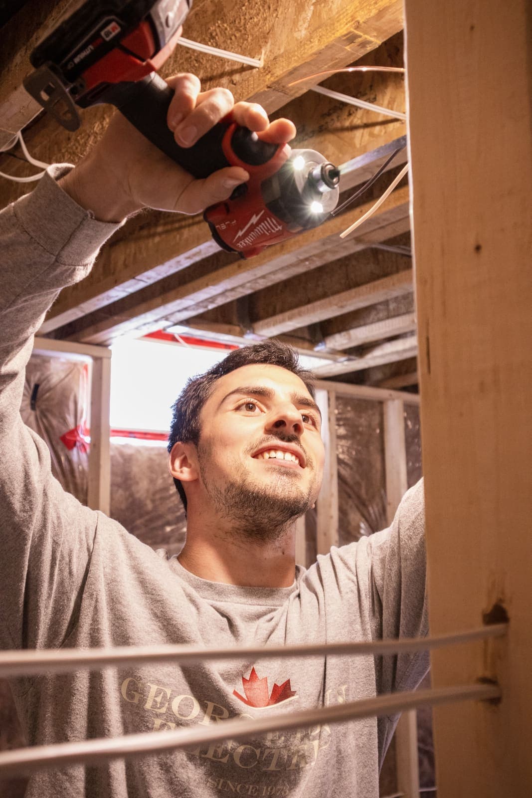 Electrician wiring the ceiling during a basement renovation