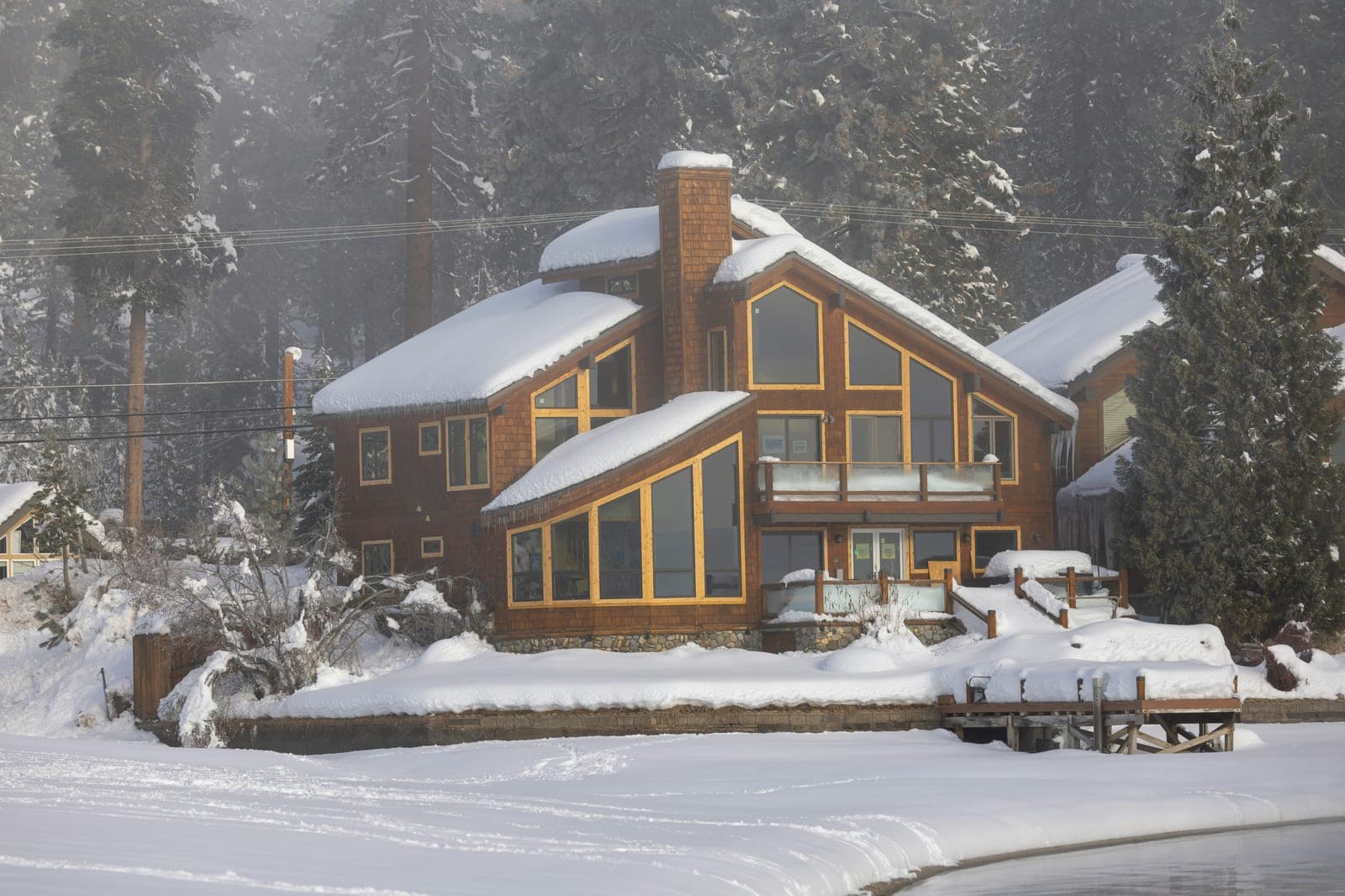 Lakeside home with the lights on through a winter fog